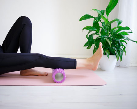 young woman doing exercises on a massage roller.の写真素材