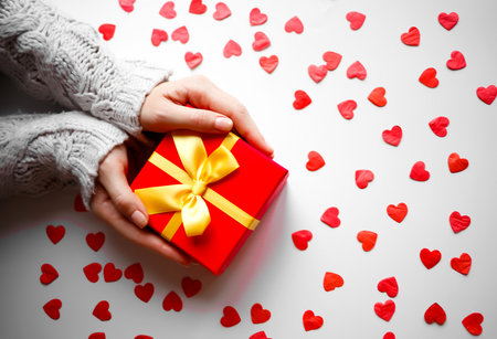hands hold a gift on a white background with red hearts.の写真素材