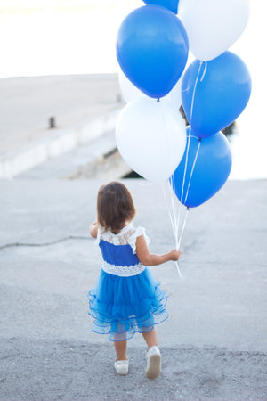 little girl in a beautiful dress with a huge fountain of balloons.の写真素材
