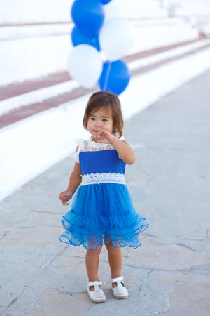 little girl in a beautiful dress with a huge fountain of balloons.の写真素材