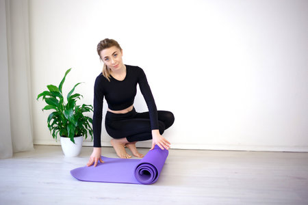 young woman unfolds yoga mat before practice.の写真素材