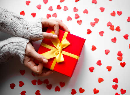 hands hold a gift on a white background with red heartsの写真素材