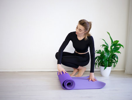 young woman unfolds yoga mat before practice.の写真素材
