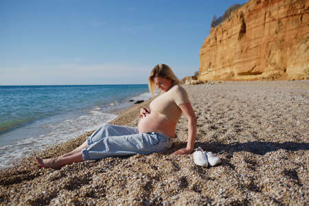 a pregnant woman sits on the seashoreの写真素材