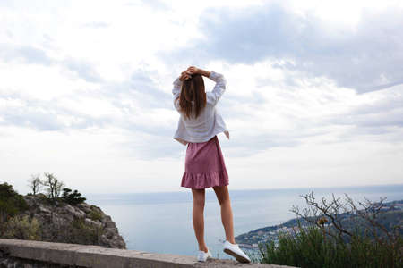 young woman stands over a cliff with her hands upの写真素材