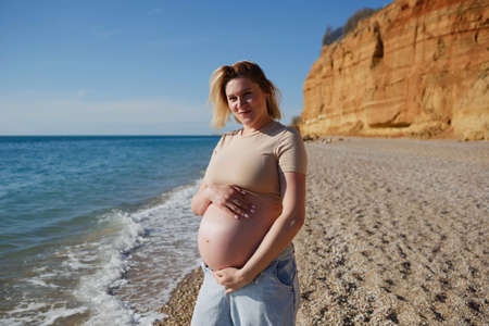 a pregnant woman standing on the seashore.の写真素材