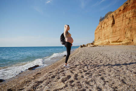 young pregnant woman with a backpack walks along the sea.の写真素材