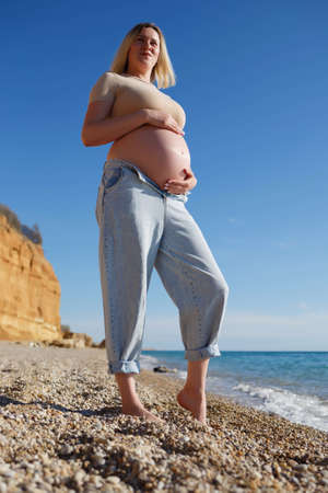 a pregnant woman standing on the seashore.の写真素材