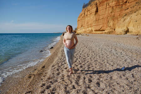 a pregnant woman walking on the seashore.の写真素材