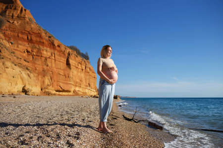 a pregnant woman standing on the seashore.の写真素材