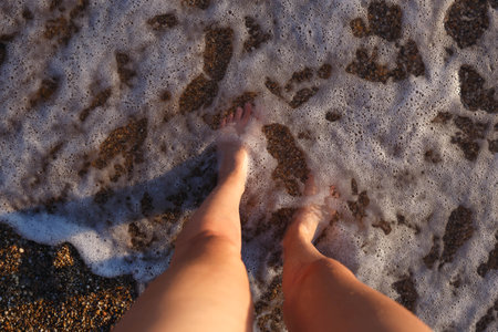 tanned legs with water drops lie on the sand at sunset. close-up.