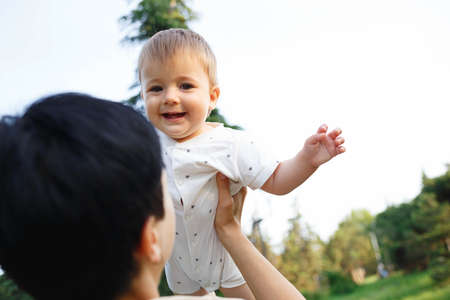 young mom kisses her little son while sitting in the park on the lawn.の写真素材
