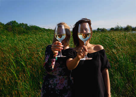 two young women holding glasses of wineの写真素材