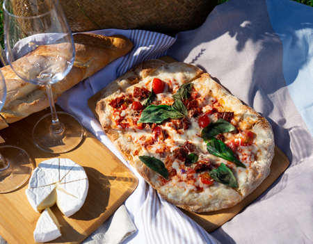 picnic in nature: pizza, cheese, baguette and glasses of wine.