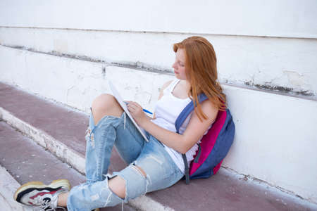 teenage girl draws in the sketchbook while sitting on the steps.の写真素材