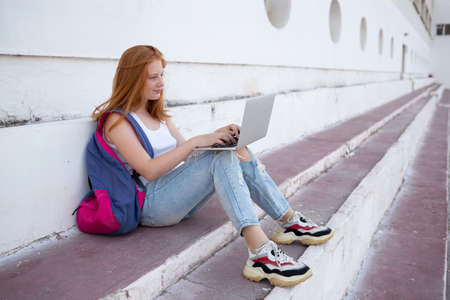 teenage girl working on laptop sitting on steps.の写真素材