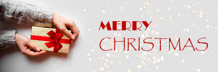 hands hold a gift on a white background with the caption: merry christmas.の写真素材