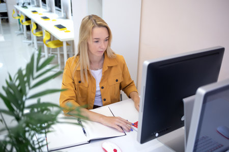 young woman sits at a computer in the office. remote work concept.