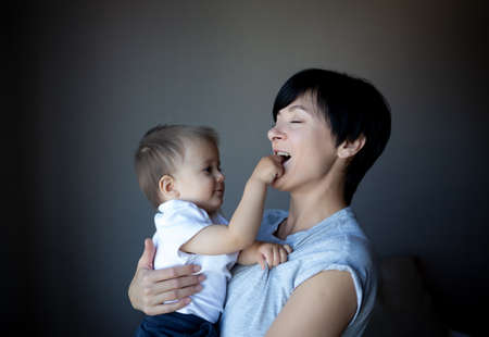 little boy plays with young beautiful mom in the bedroom.の写真素材