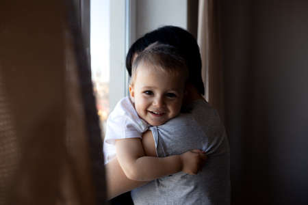 little boy with his young beautiful mother look out the window.の写真素材