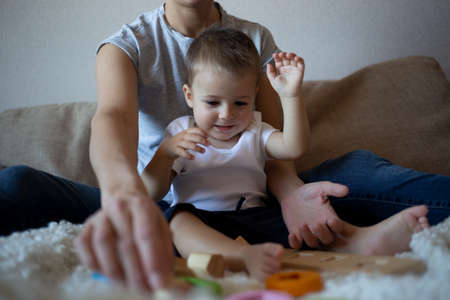 little boy plays with young beautiful mom in the bedroom.の写真素材