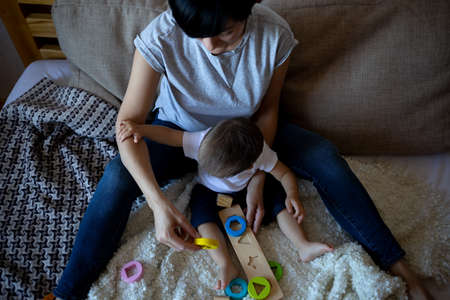 little boy plays with young beautiful mom in the bedroom.の写真素材