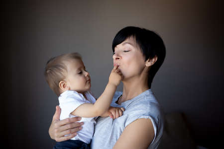 little boy plays with young beautiful mom in the bedroom.の写真素材