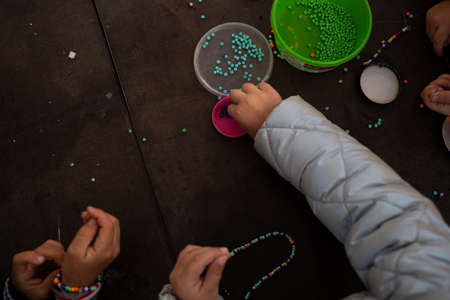 little children's hands weave a bead bracelet close-up shot.の写真素材