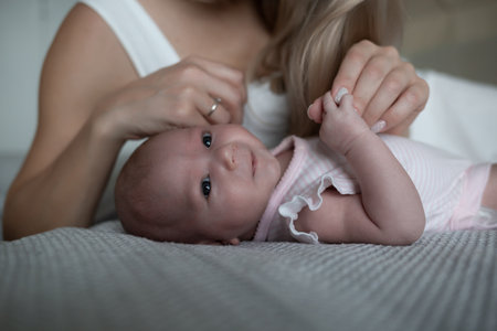 little cute baby girl lies in her mother's arms.の写真素材
