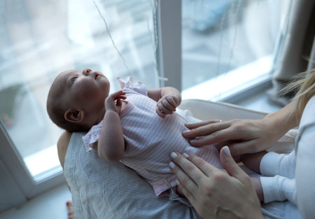 little cute baby girl lies in her mother's arms.の写真素材