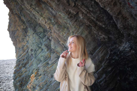 portrait of a young beautiful woman on the seashore against the background of rocks.
