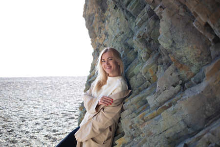 portrait of a young beautiful woman on the seashore against the background of rocks.の写真素材