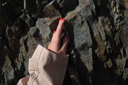 close up shot. female hand with beautiful manicure on texture stone.