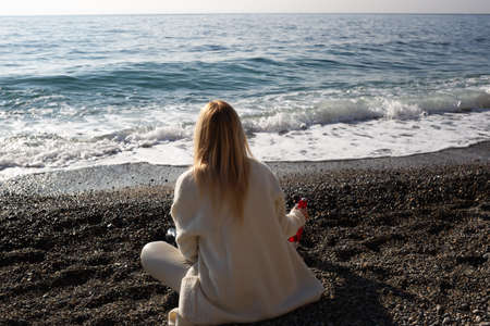 young beautiful woman on the seashore against the background of rocks.