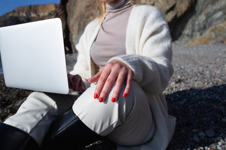 young beautiful woman working on a laptop sitting on the beach.の写真素材