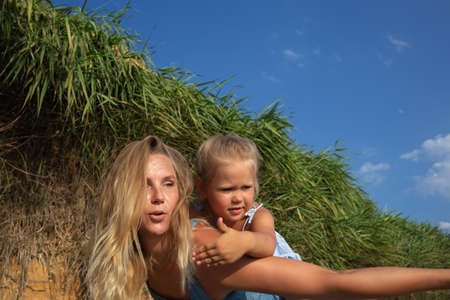 little girl hugging her mom at sunset on the beach near the sea. family portraitの写真素材