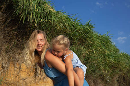 little girl hugging her mom at sunset on the beach near the sea. family portraitの写真素材