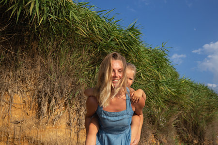 little girl hugging her mom at sunset on the beach near the sea. family portraitの写真素材