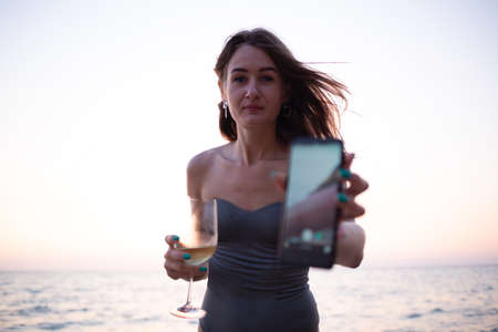 portrait of a woman typing a text message on the phone on the seashoreの写真素材