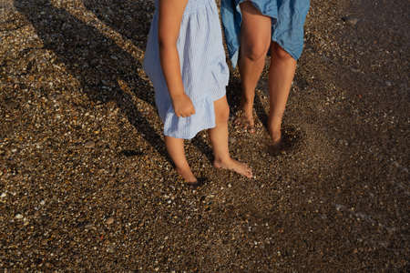 close-up shot, mother and daughter walking barefoot along the seashoreの写真素材