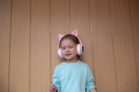 portrait of a little cute girl dancing with headphones on her headの写真素材