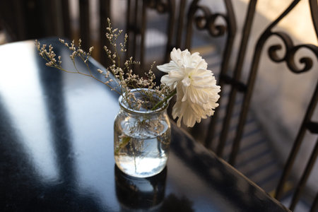beautiful fresh white flower in a transparent small vase on a black table in a restaurant. minimalist composition.の写真素材