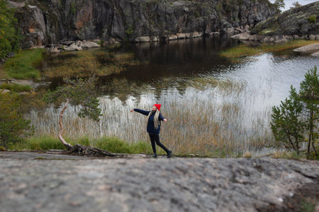 young beautiful girl in the autumn forest against the backdrop of a large lakeの写真素材