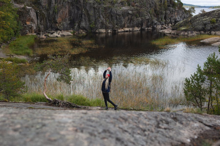 young beautiful girl in the autumn forest against the backdrop of a large lakeの写真素材