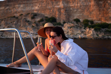 two young women at sunset are resting on a yacht in the open seaの写真素材
