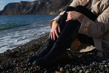 close-up shot. female hands hugging knees sitting on the seashore.の写真素材