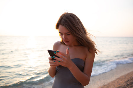portrait of a woman typing a text message on the phone on the seashoreの写真素材