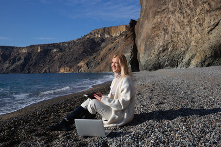 young beautiful woman working on a laptop sitting on the beachの写真素材
