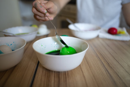young beautiful woman in bunny ears paints eggs for easter in the kitchen.の写真素材