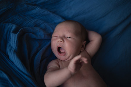 mixed race newborn baby lies wrapped in a blue muslin swaddle.の写真素材